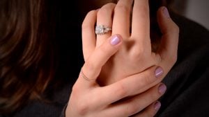Woman showing hand wearing engagement ring