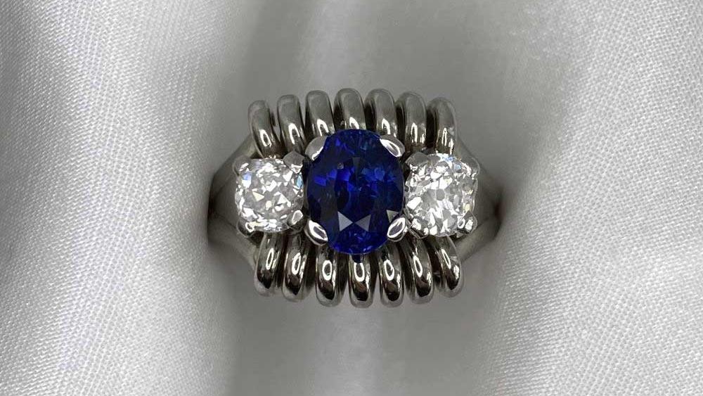 A sapphire and two diamond three stone ring with a coil motif mounting.