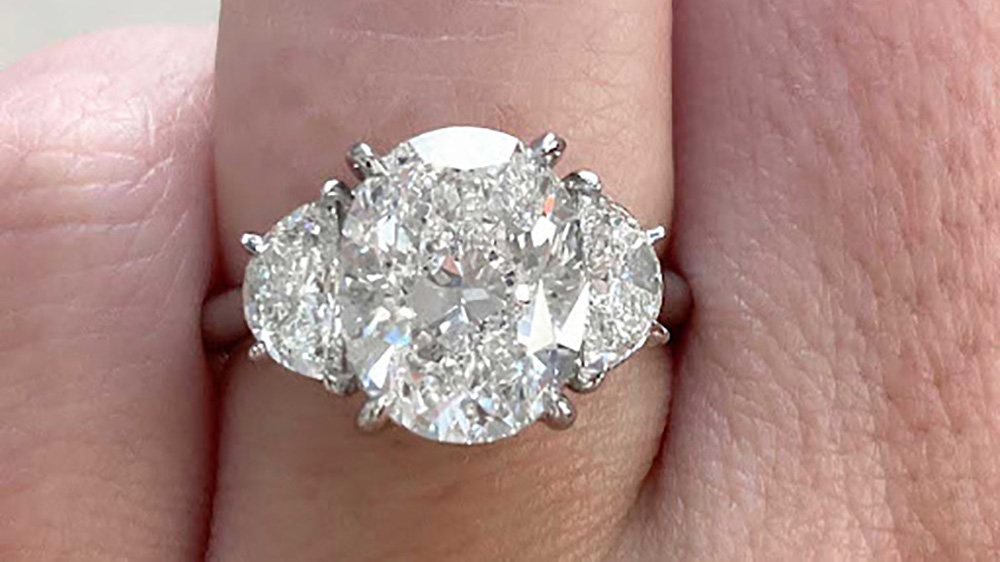 three stone platinum ring with oval cut center diamond and half moon side diamonds