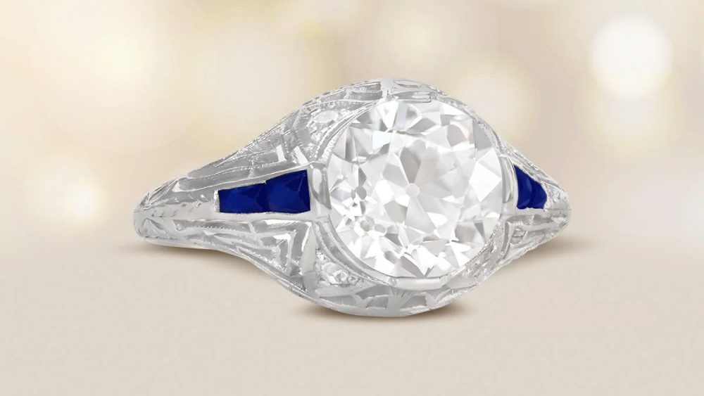 A rounded diamond ring with sapphire-accented shoulders.