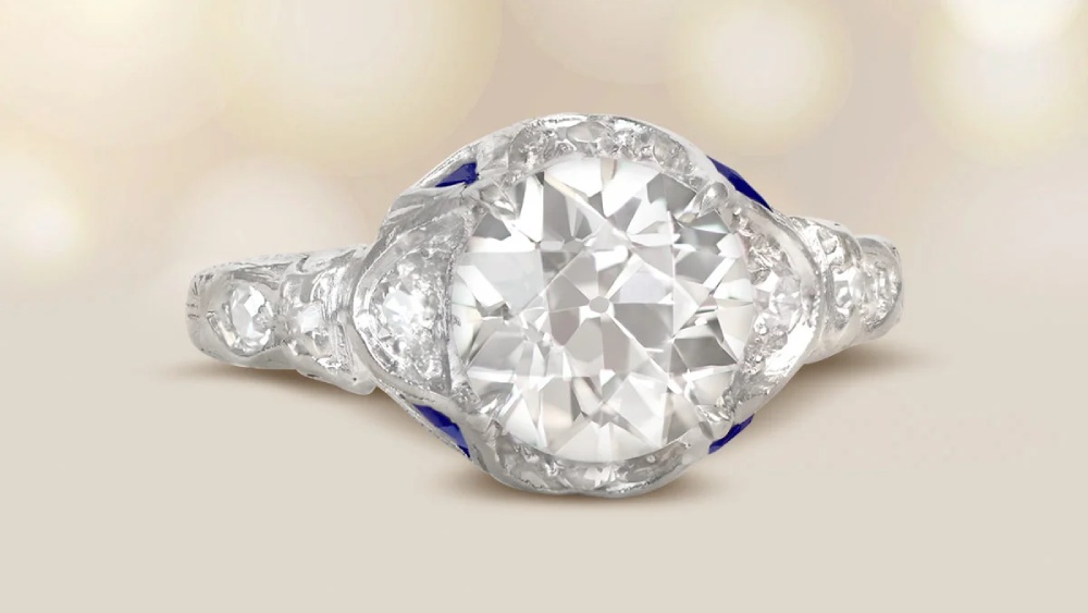 A diamond ring with sapphire accents and a unique shape.