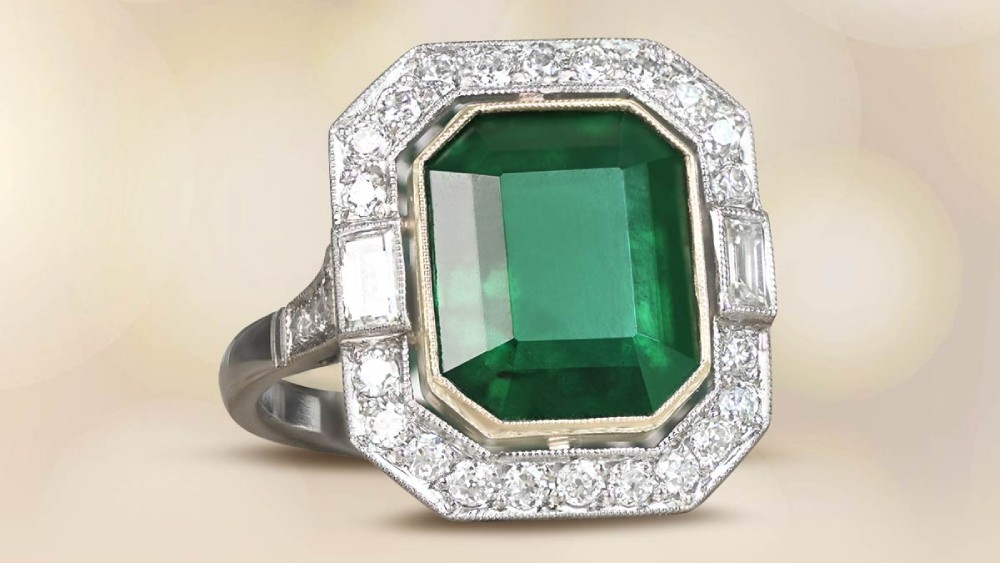A large emerald-cut emerald ring with a diamond halo.