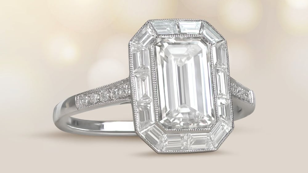 An emerald cut diamond ring with a halo of baguette diamonds.