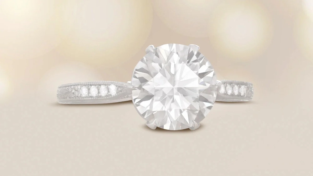 A solitaire diamond ring with diamond-set shoulders and detailed engravings.