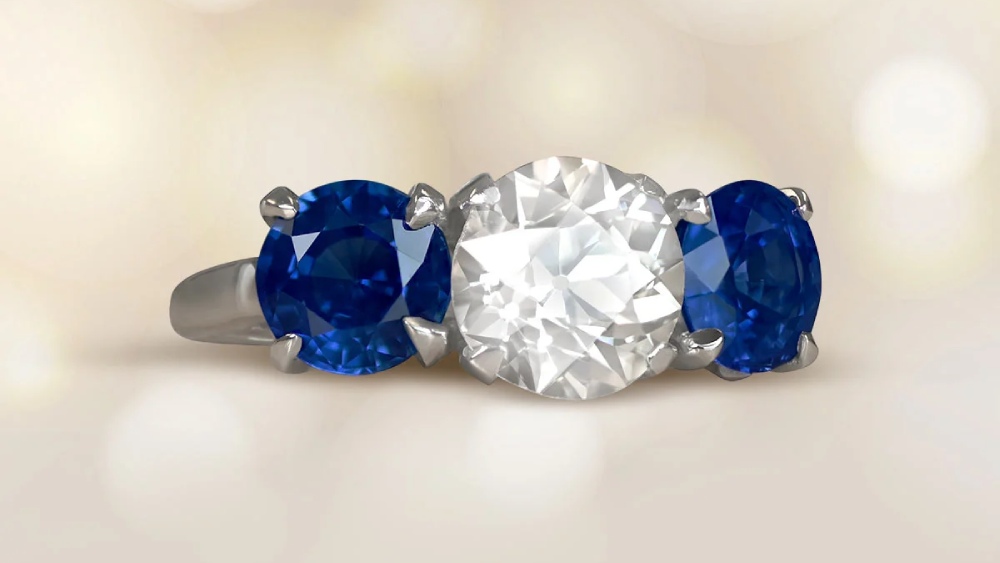 A three stone ring featuring a diamond and two sapphires.