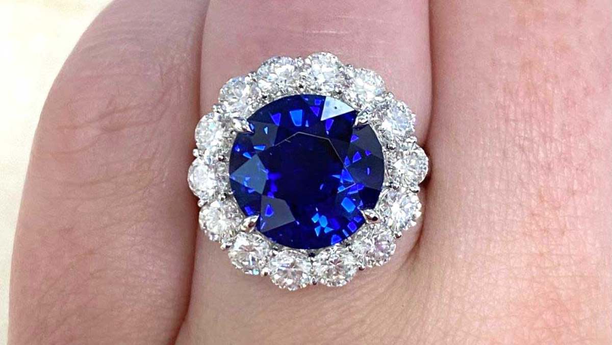 platinum engagement ring featuring large deep blue sapphire and floral diamond halo