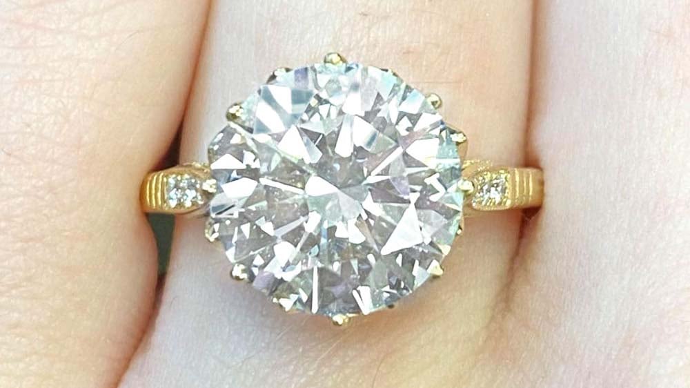 A solitaire diamond ring with an embellished yellow gold mounting.