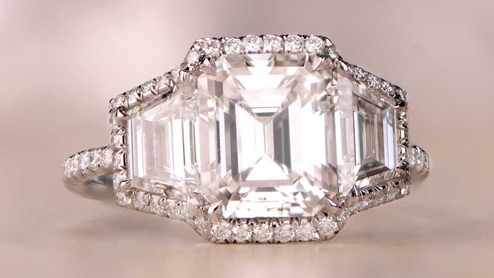 A three-stone ring with an emerald-cut and two trilliant-cut diamonds.