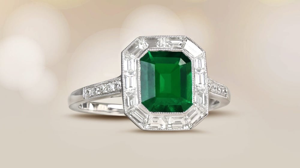 An emerald cut emerald ring with a diamond halo.