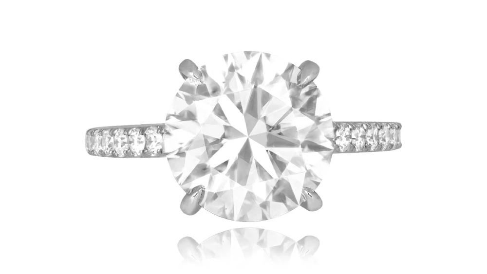 A solitaire diamond ring with diamond lined-shoulders.