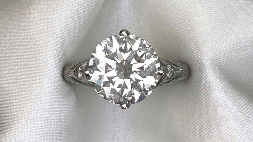 A solitaire diamond ring with a crown setting and engraved mounting.