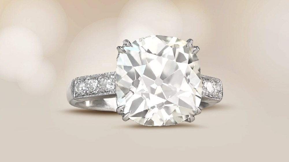 An antique cushion cut diamond ring with adorned shoulders.