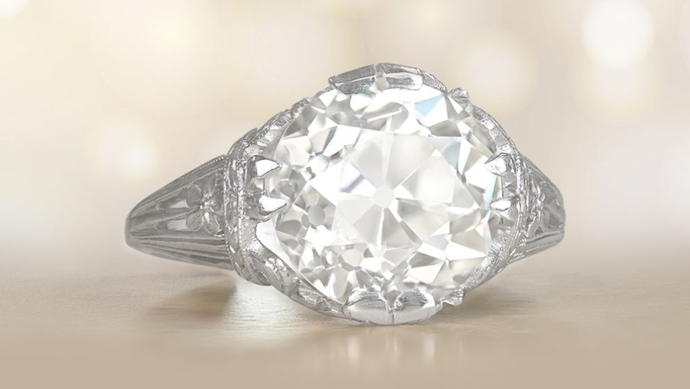 A diamond ring with an ornate openwork mounting and tapered shoulders.
