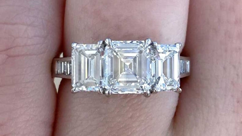 A three-stone ring feature an Asscher and two emerald diamonds.