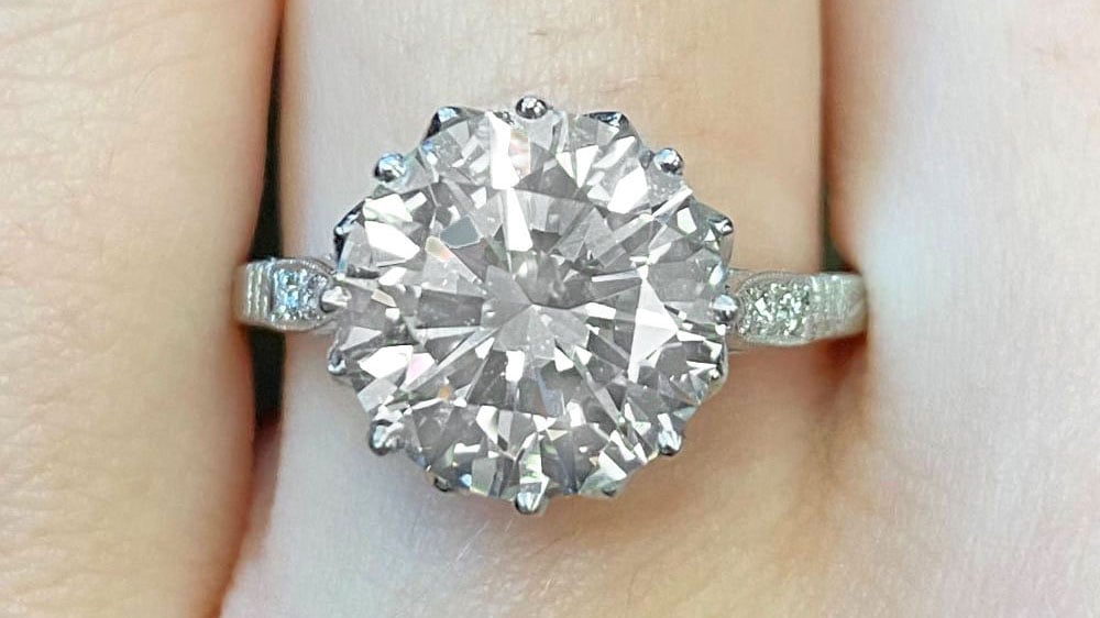 A solitaire diamond ring with milgrain and diamond shoulders.