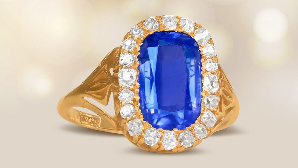 A yellow gold elongated sapphire ring with a diamond halo.