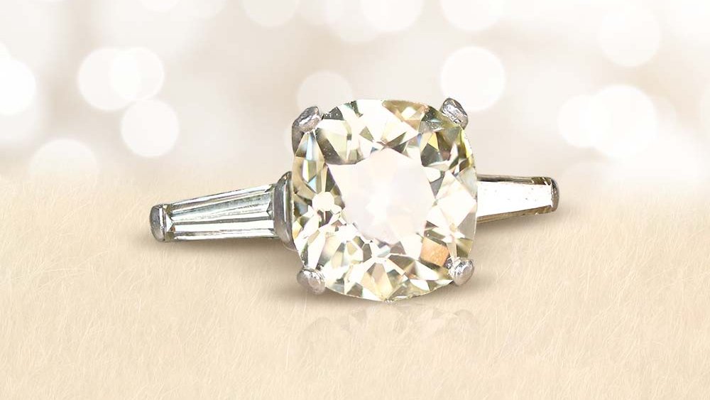 A yellow cushion-cut diamond ring with long tapered baguette diamond shoulders.