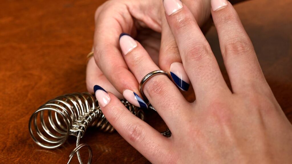 Woman using metal ring sizer tool at home measure