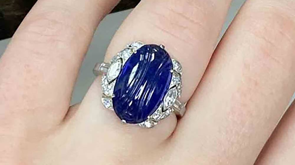A deep blue sapphire ring with many diamond accents.