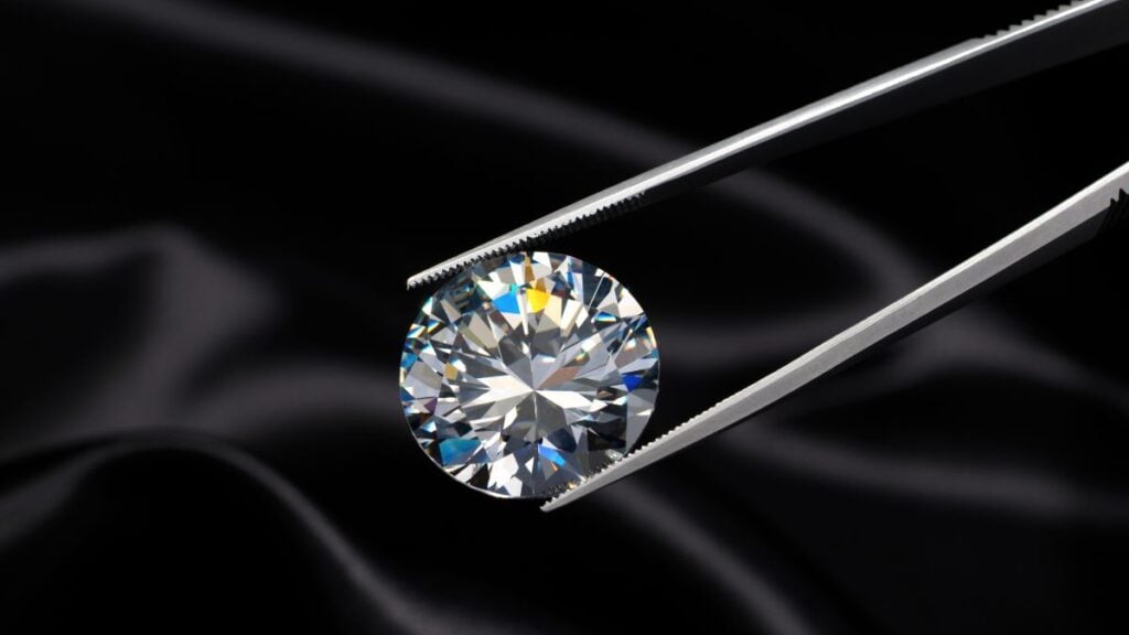 loose E colored diamond on tweezers against black backdrop