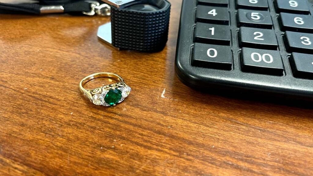 Zambian Emerald next to loupe and calculator