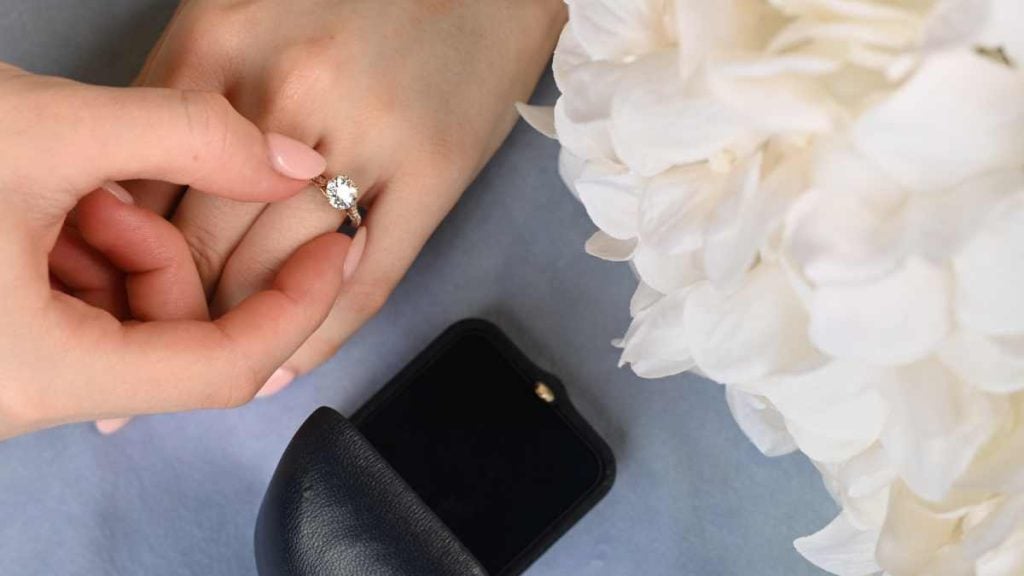 Woman hand shopping for engagement ring with box flowers