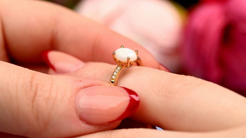 Close up of opal birthstone ring with diamonds yellow gold