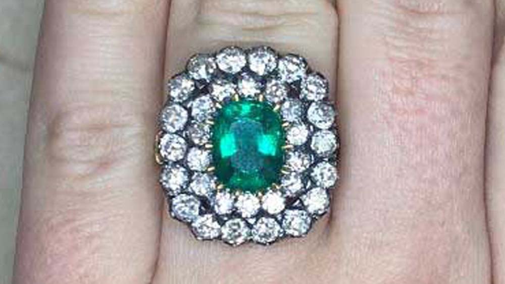 A double diamond halo ring with an emerald set in gold.