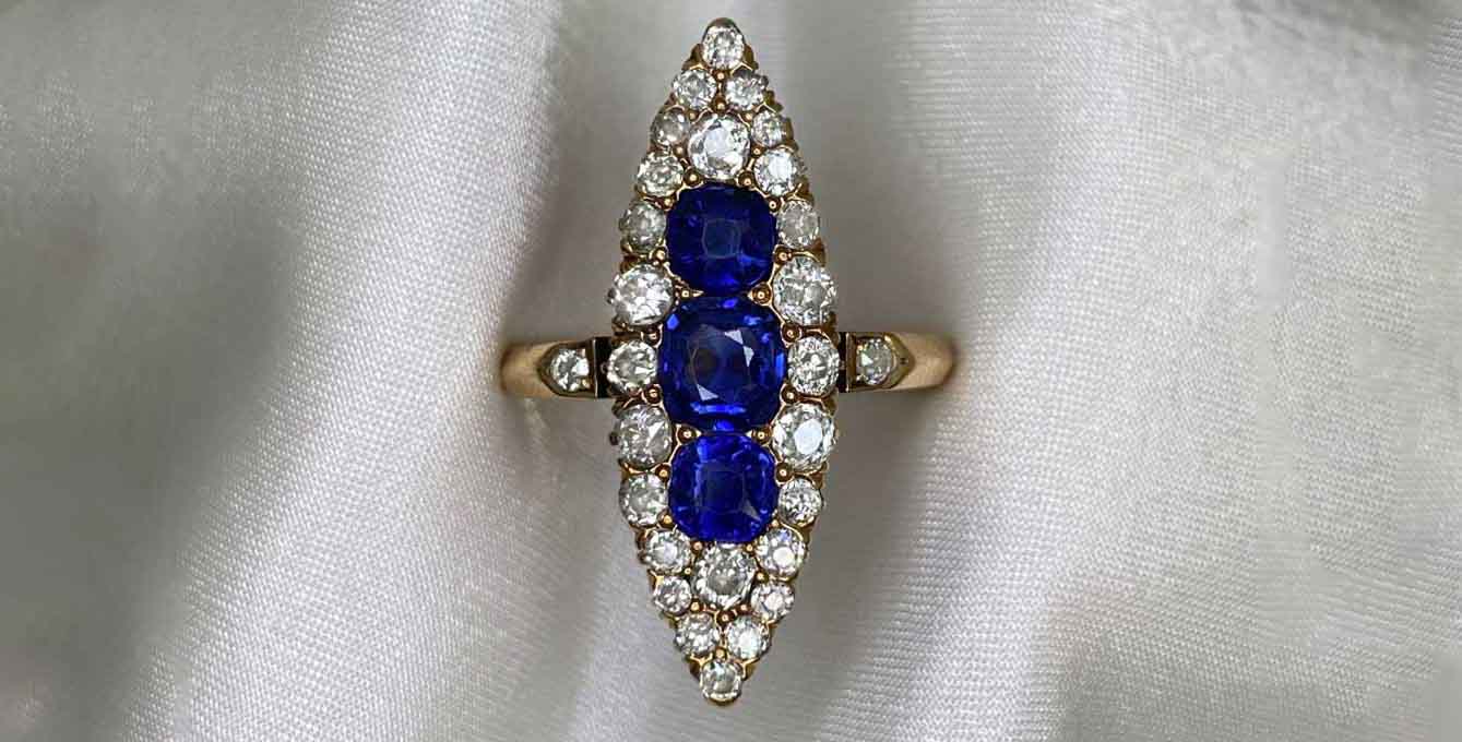 A yellow gold navette ring featuring sapphires and diamonds.
