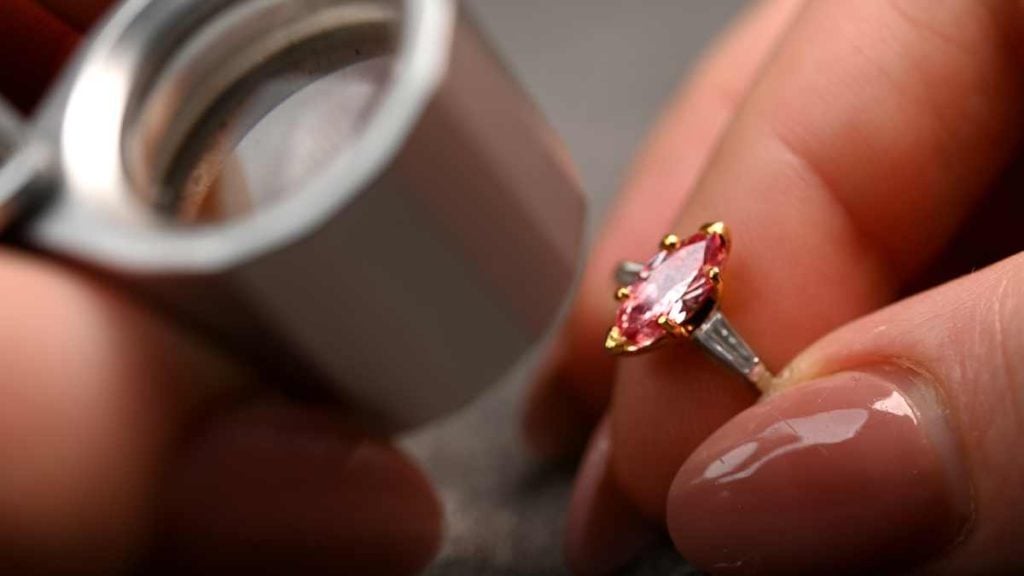 Jeweler examining rare marquise cut red diamond in gold ring